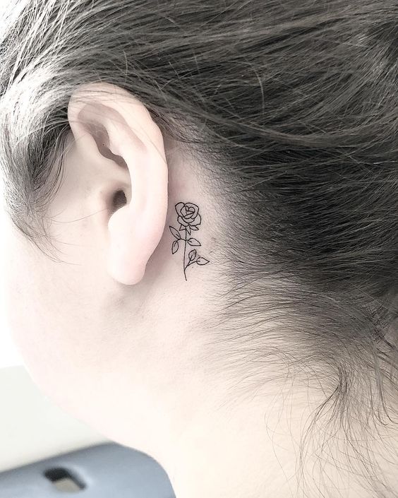 Una flor tribal tatuada detrás de la oreja