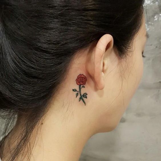 Un tatuaje de una rosa tatuada detrás de la oreja