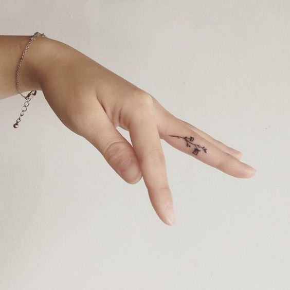 Tatuajes pequeños de flores en el dedo anular