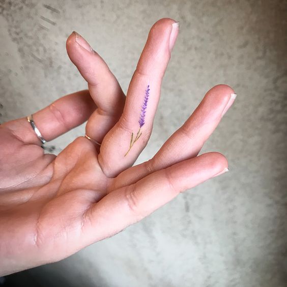 Una flor diminuta tatuada en el dedo de la mano