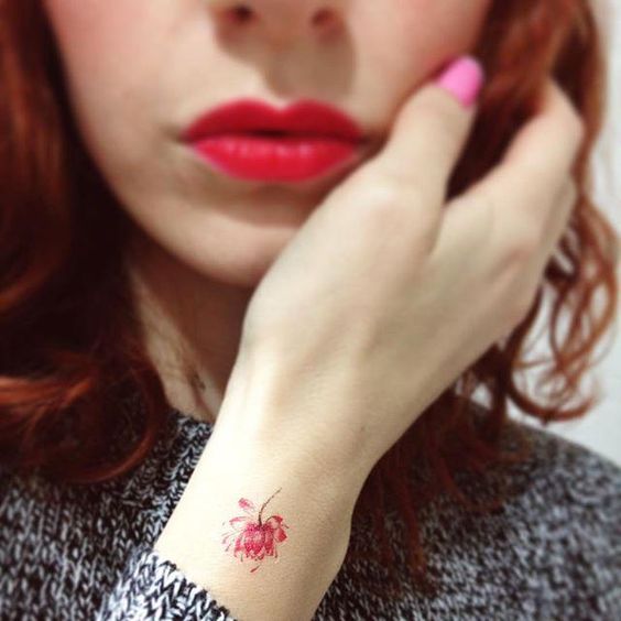 Flor roja tatuada en la mano