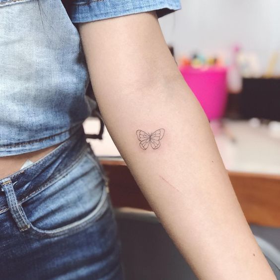 Mariposa pequeña con un diseño simple tatuada en el brazo