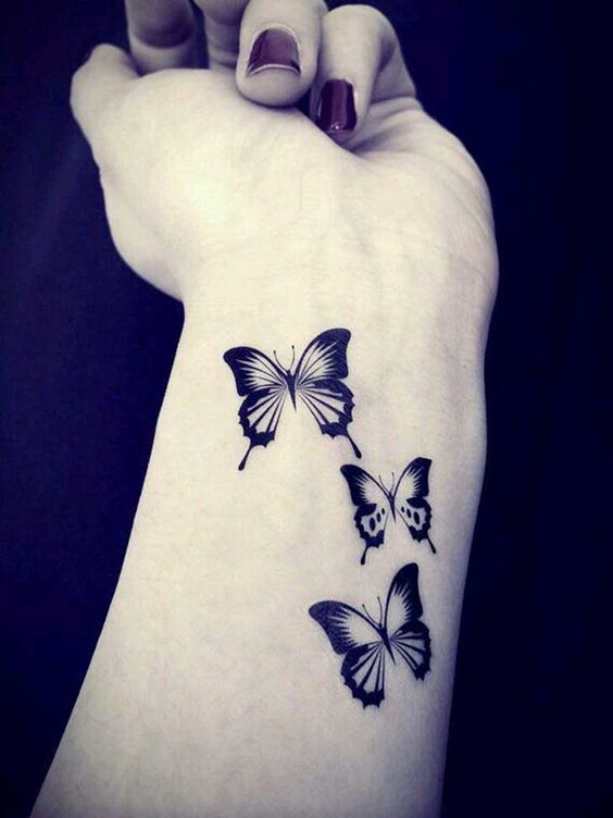 tres mariposas tatuadas en el antebrazo de una mujer