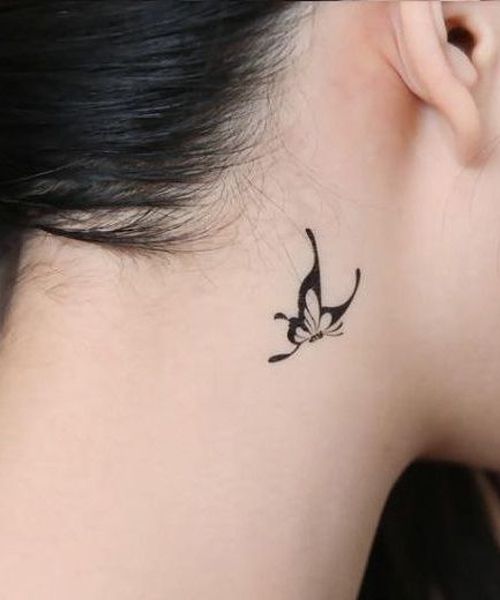 Una mariposa tribal tatuada detrás de la oreja