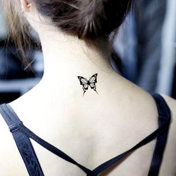 Un tatuaje de una mariposa tribal tatuado en la parte baja de la nuca en una mujer joven