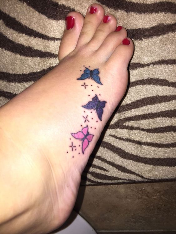Mariposas y puntos tatuados en el pie de una chica