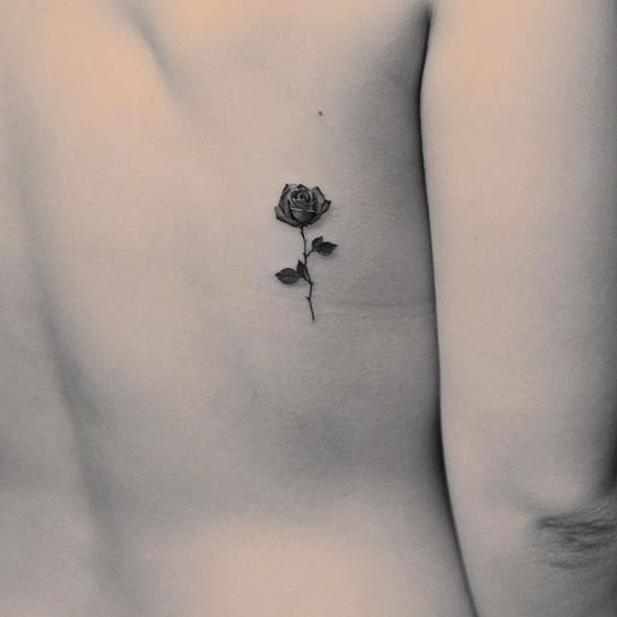 Rosa florescida de color negro tatuada en la espalda