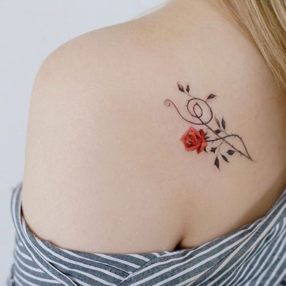 Una rosa junto a un símbolo musical tatuada en la espalda cerca del hombro