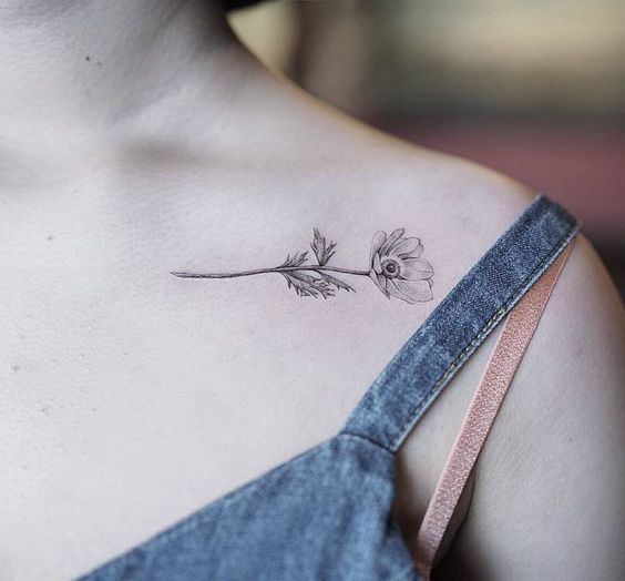 Uma garota com uma tatuagem simples de rosa no ombro esquerdo