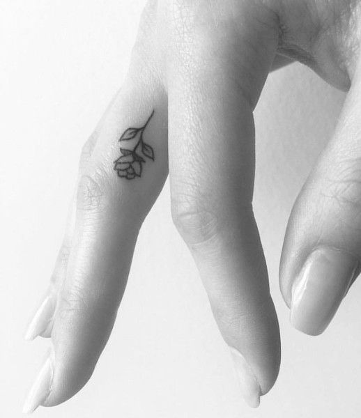 Una rosa muy pequeña tatuada en el dedo de la mano