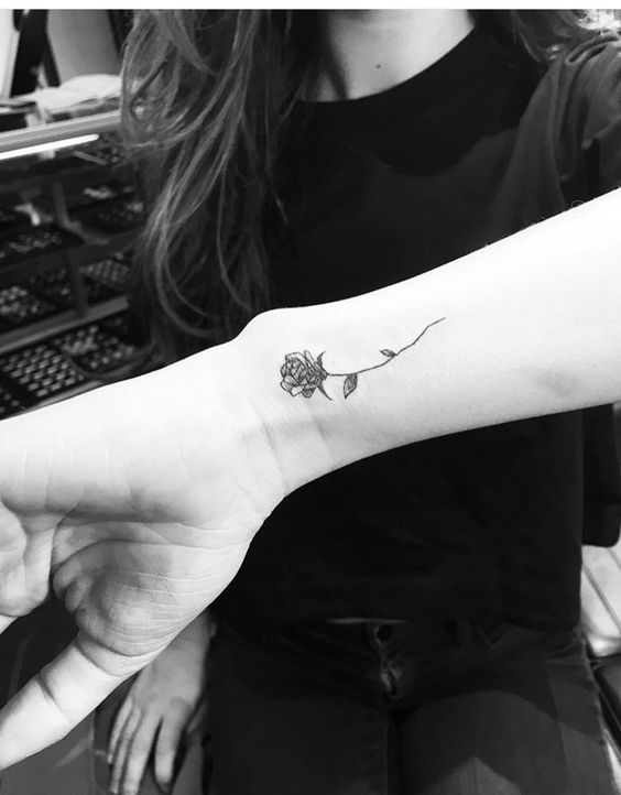Rosa pequeña de color negro tatuada en la mano
