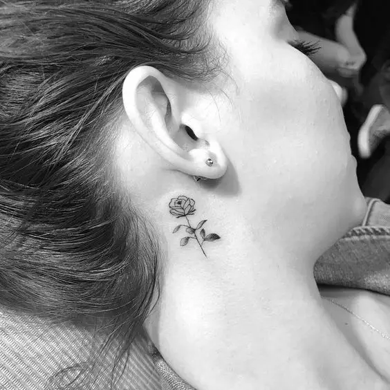 Menina com uma pequena tatuagem de uma rosa no pescoço