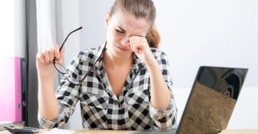 Frotarse los ojos puede deformar la córnea. Mujer frotando sus ojos.