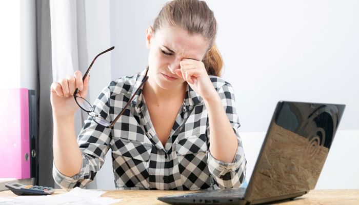 Frotarse los ojos puede deformar la córnea. Mujer frotando sus ojos.