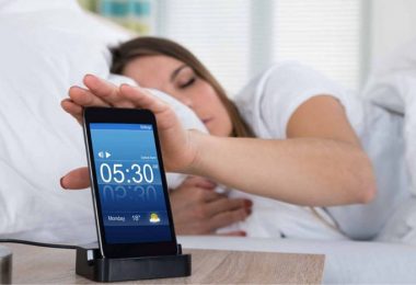 Mujer posponiendo alarma por no poder levantarse por las mañanas