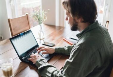 hombre escribiendo en computadora para trabajo en casa