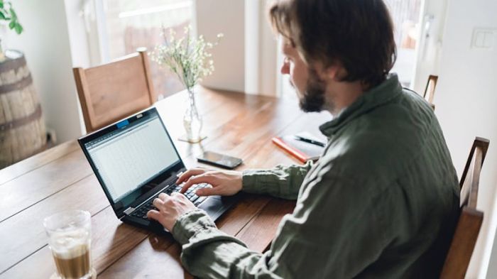 hombre escribiendo en computadora para trabajo en casa