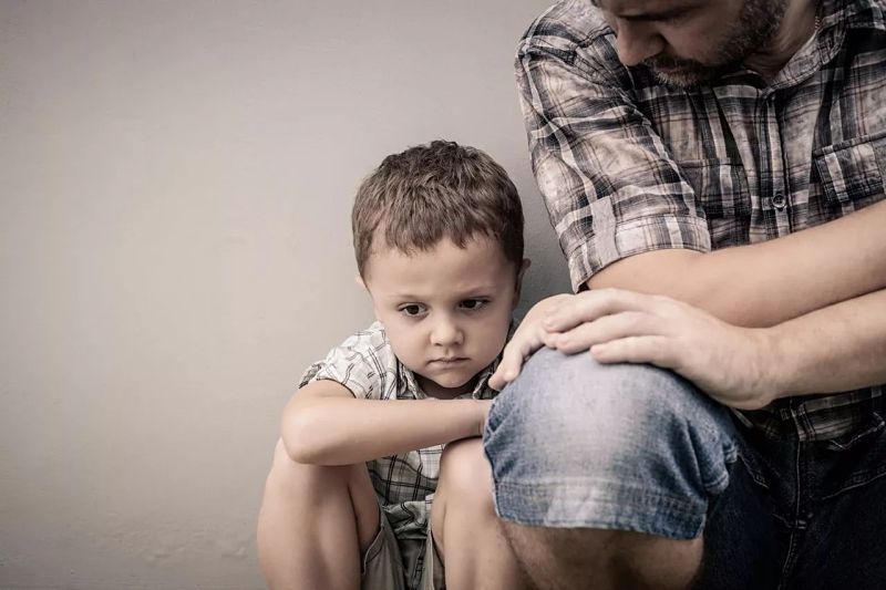 Padre junto a su hijo que está triste por el encierro y no ver a sus amigos