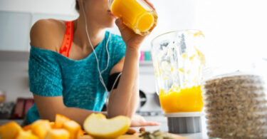 Mujer que hace deporte tomando jugo de naranja