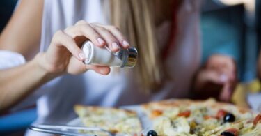 Mujer agregando sal a la comida