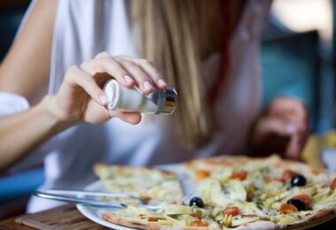 Mujer agregando sal a la comida
