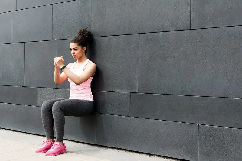 Femme faisant des squats contre le mur