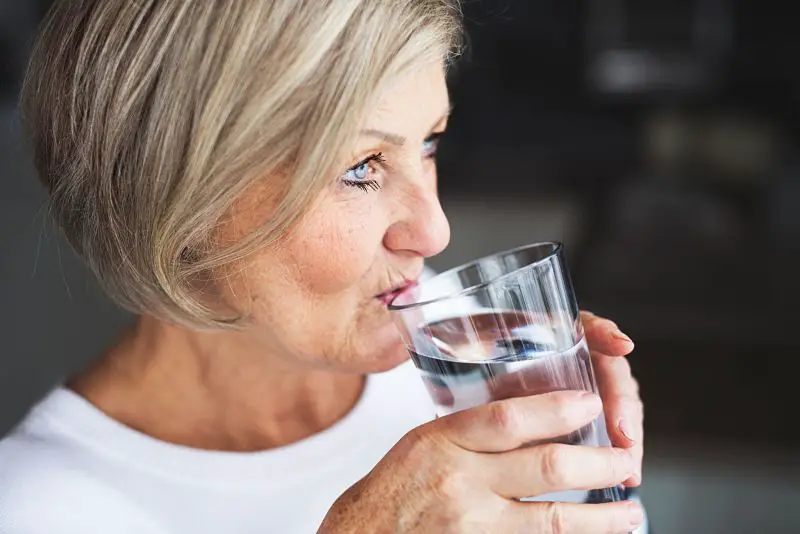 Mujer bebiendo agua para prevenir la osteoporosis