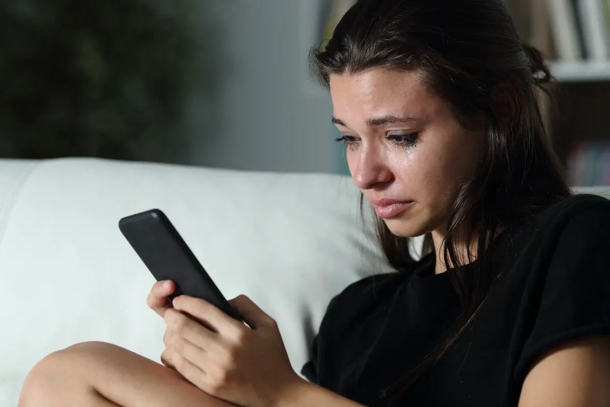 Mujer llorando al bloquar a su ex en las redes sociales