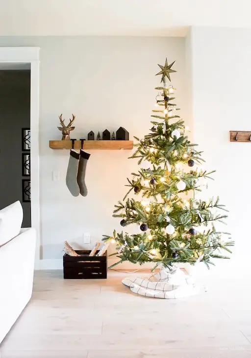 calcetines de navidad colgados en estanteria abierta acompañados por un pino navideño 