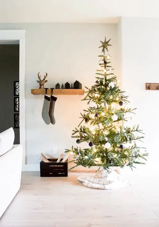 calcetines de navidad colgados en estanteria abierta acompañados por un pino navideño
