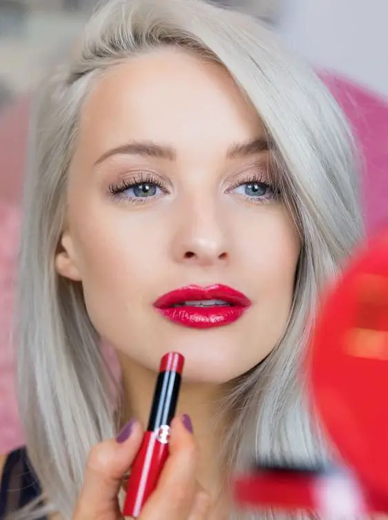 mujer con canas pintándose los labios rojos