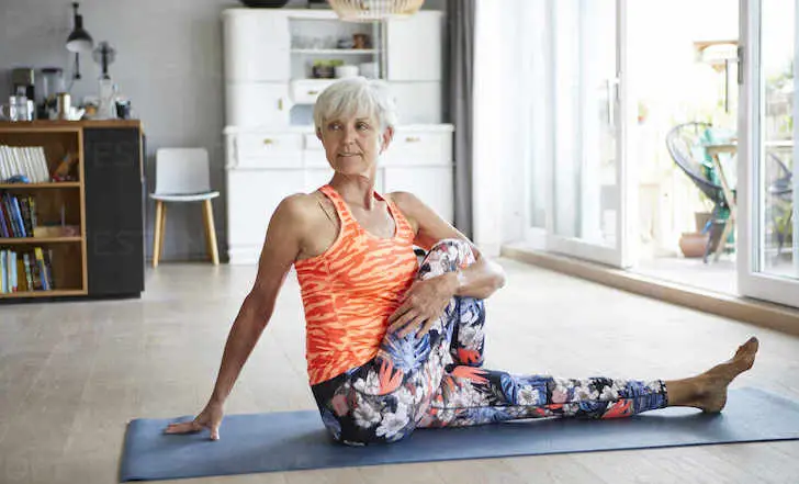 mujer de 50 y más haciendo yoga con ropa deportiva de colores
