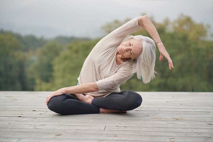 mujer de mediana edad haciendo posturas de yoga con ropa deportiva