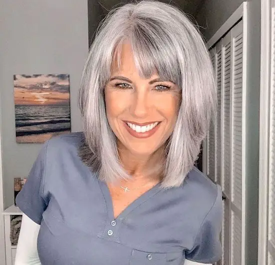 mujer con canas sonriendo peinado lob y blusa gris