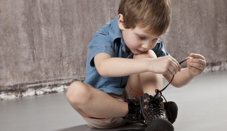 niño pequeño amarrándose solo las agujetas de sus zapatos