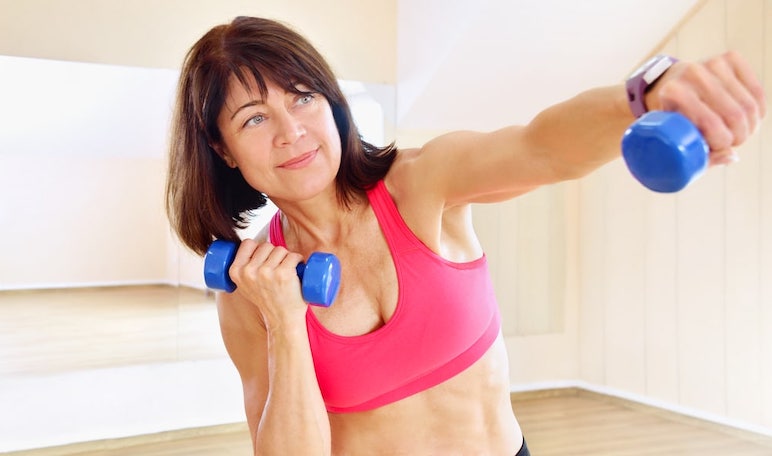 mujer de mediana edad top rosa levantando mancuernas