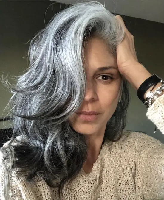 mujer con canas reflejos en el pelo highlights