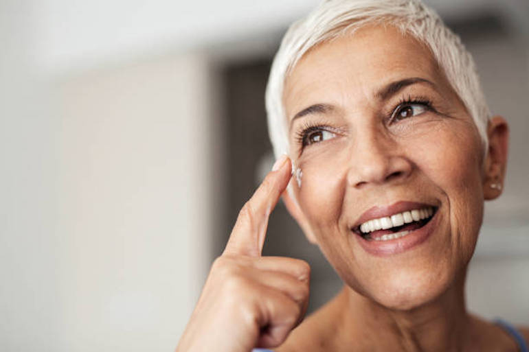 mujer soriendo mediana edad pelo corto canas crema en rostro