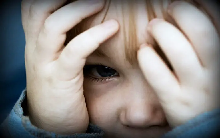 niño pequeño llorando manos en cara