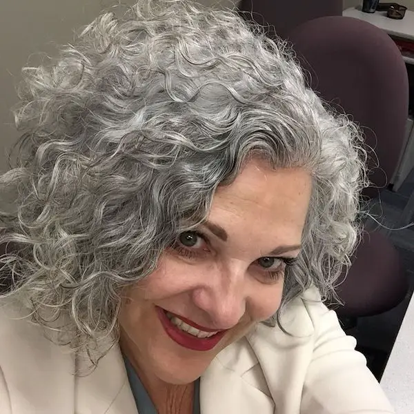 mujer sonriente con cabello canoso rizado